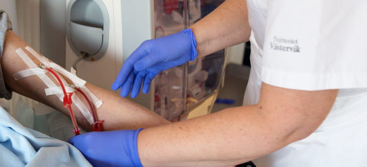 Vårdperson i kortärmat hjälper en patient.