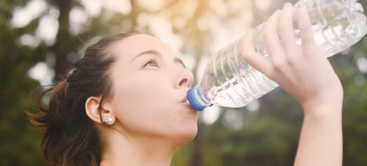 Bild på kvinna som dricker vatten ur en flaska.