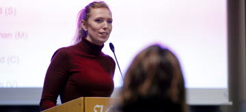 Malin Anell (S) står talarstolen under ett regionfullmäktige.