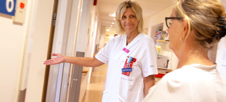 Vårdanställd som välkomnar en patient till ett undersökningsrum.