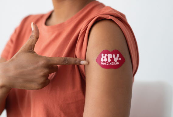 En person som visar axeln där det sitter ett plåster med texten HPV-vaccinerad.