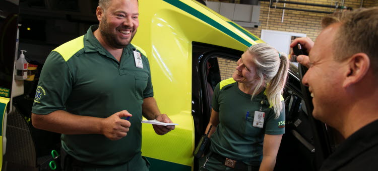 Ambulanssjuksöterskor står framför en ambulans.