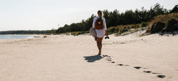 Bild från Bödabukten där en kvinna går på stranden.