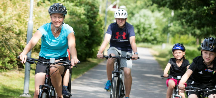 Familj som cyklar i solsken.