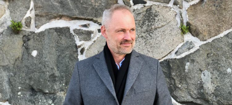 Man framför en stenmur.