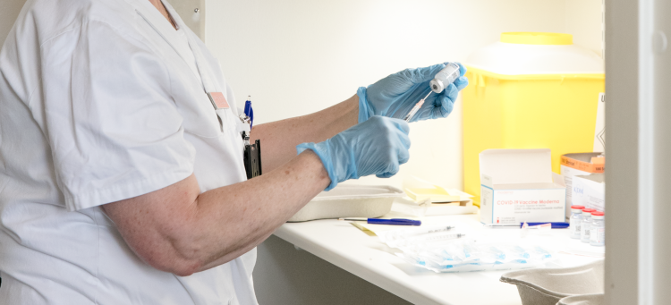 En vårdpersonal som har handskar på sig och drar upp läkemedel i en spruta.
