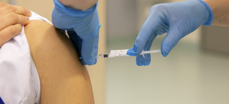 Bild på en person som får en vaccinspruta i armen.