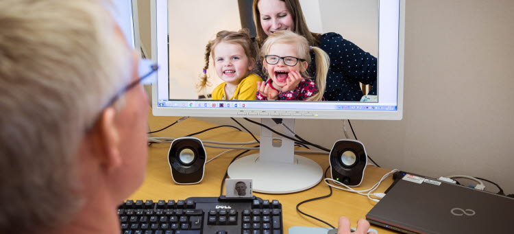 Person som sitter vid en datorskärm med bild av en familj 