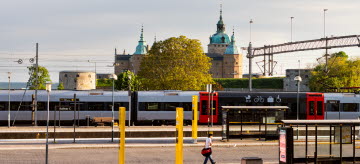 Ett Öresundståg står parkerat på centralstationen i Kalmar med Kalmar slott i bakgrunden.