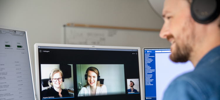 En person sitter med headset framför en skärm och har ett digitalt möte.