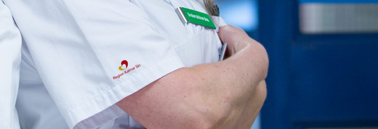 Vårdpersonal i närbild med Region Kalmar läns logotyp på tröjärmen.